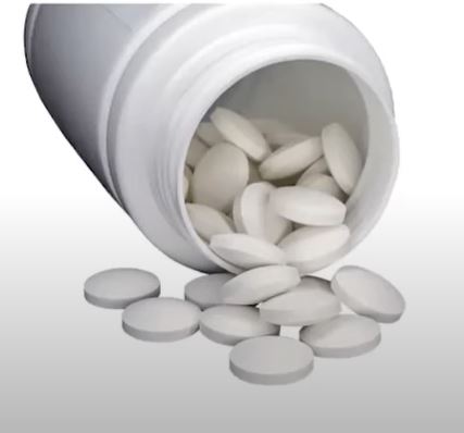 a white medicine bottle on its side with white pills spilling out