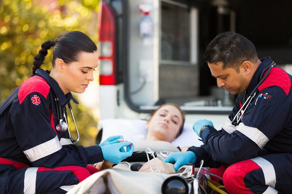 paramedics checking overdose patient at back of ambulance